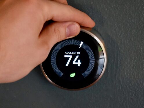 Someone adjusting a smart thermostat in their home